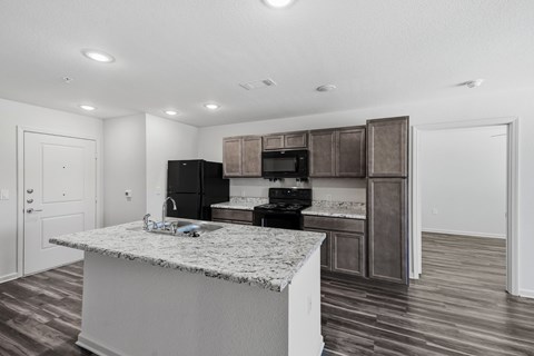A kitchen with a marble countertop and wooden cabinets.