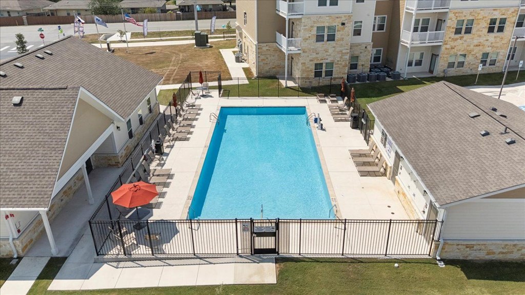 A swimming pool surrounded by a fence and a building in the background.