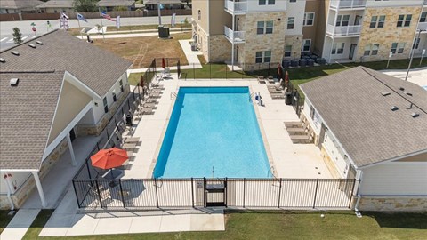 A swimming pool surrounded by a fence and a building in the background.