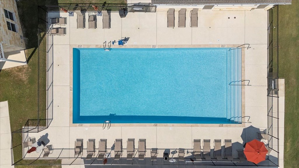 A large blue swimming pool surrounded by lounge chairs and umbrellas.