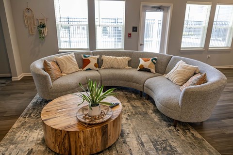 A living room with a large couch and a coffee table with a plant on it.