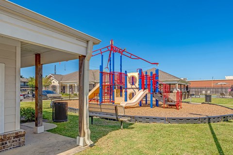 A playground with a red and blue swing set.