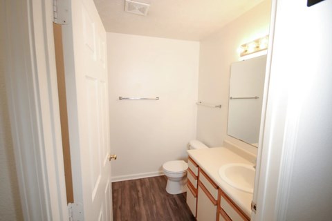 A white bathroom with a toilet, sink and mirror.