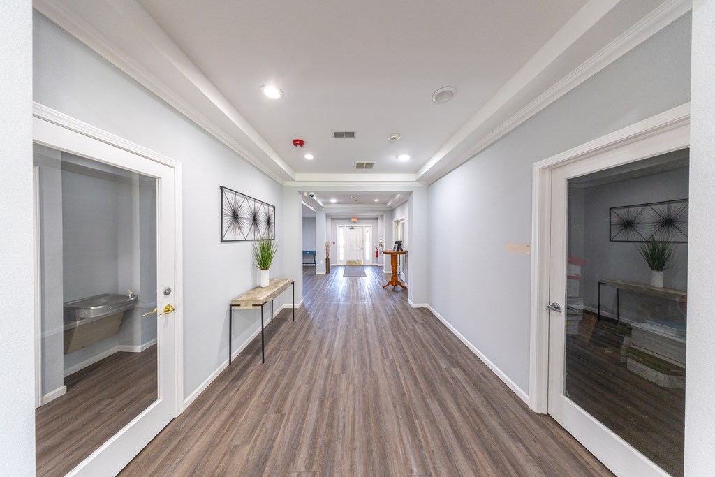 A long hallway with a bench and a plant.