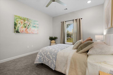 A bedroom with a large bed and a painting of flamingos on the wall.