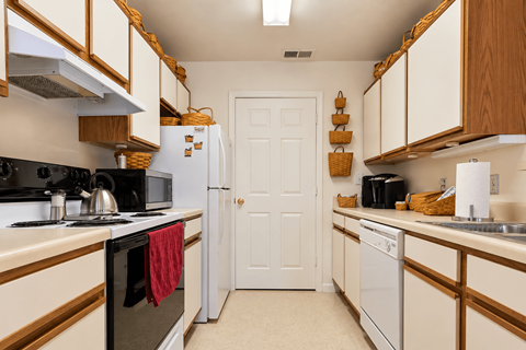 A kitchen with white appliances and wooden cabinets.