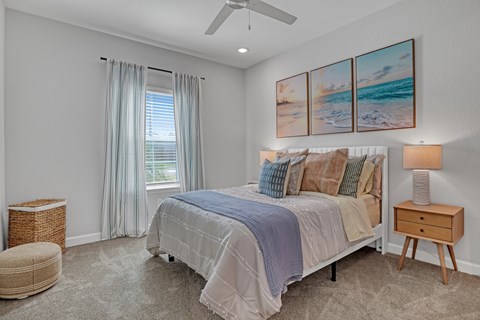 A bedroom with a large bed and a painting of a beach scene on the wall.