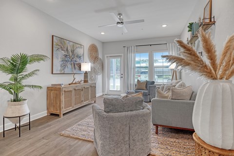 A living room with a grey couch, a wooden cabinet, a potted plant, and a painting on the wall.