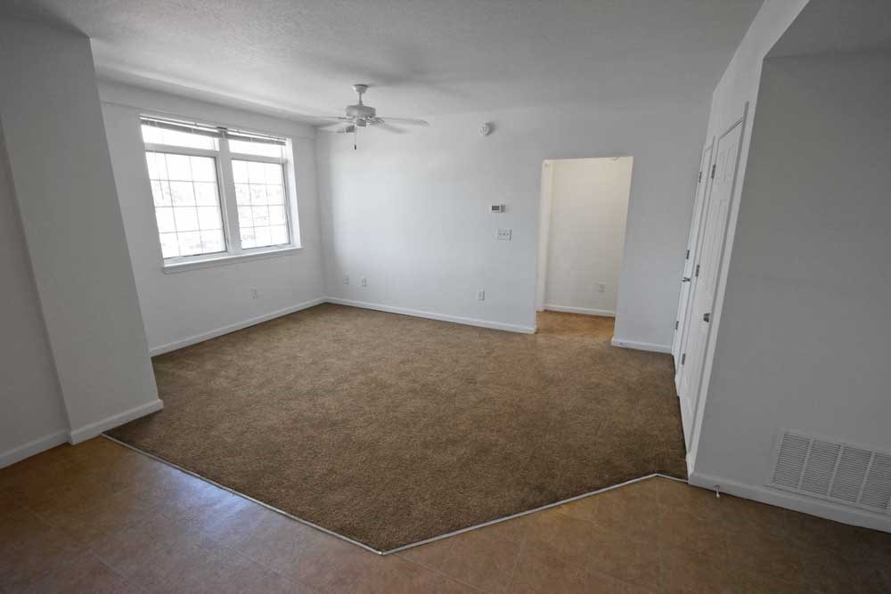 an empty room with a ceiling fan and a window