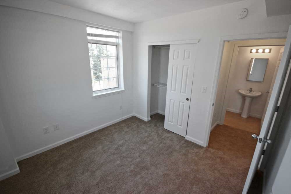 an empty bedroom with a closet and a bathroom in the background at The Enclave at Meridian apartments