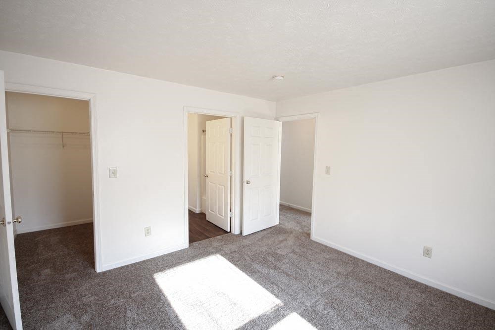 Empty bedroom with a closet and an open door at Canterbury House apartments in Warsaw, IN