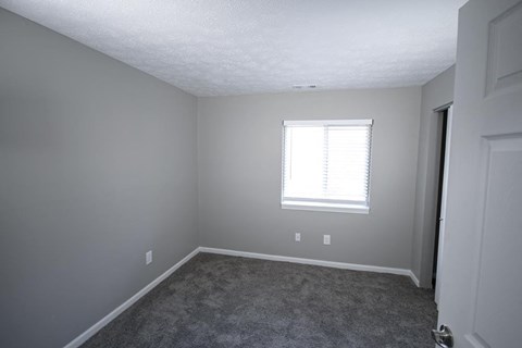 Empty bedroom with a window and a door.