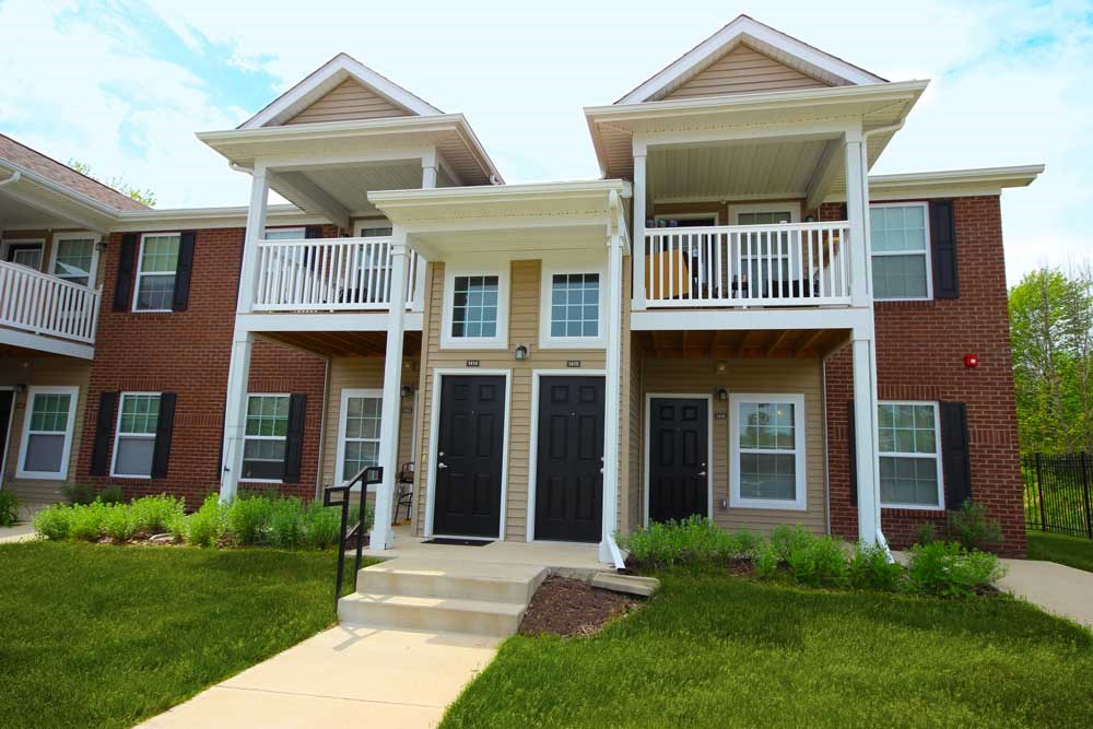 A two-story house with a black front door and white railings.