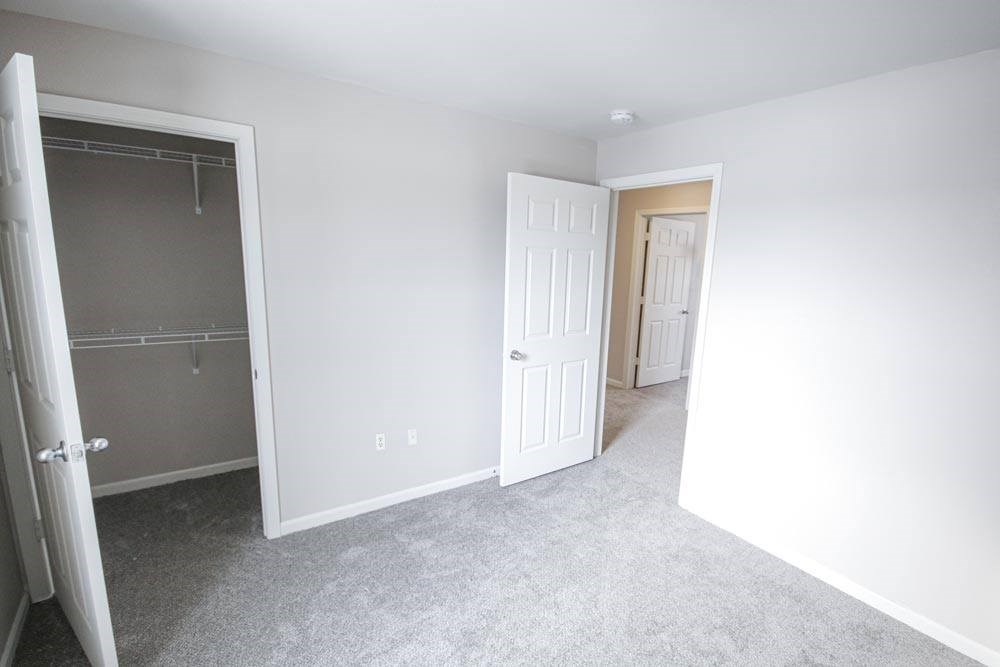 A white door is open to a room with a grey carpet.
