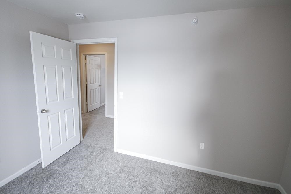 A room with a white door and carpeted floor.