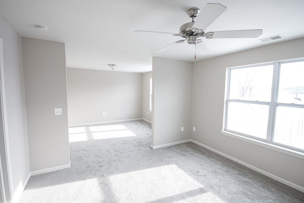 A room with a ceiling fan and a window letting in sunlight.