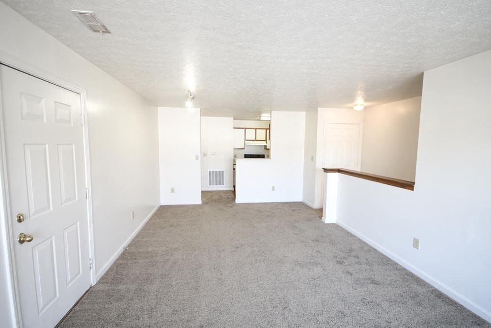 An empty living room with a kitchen in the background at Canterbury House apartments in Warsaw, IN