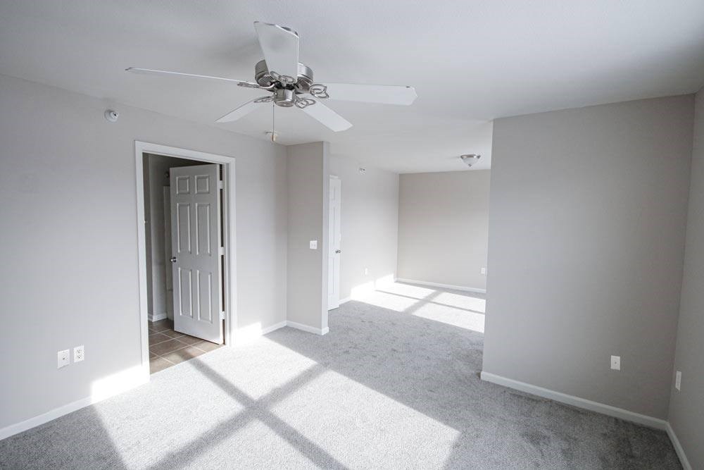 A room with a ceiling fan and a doorway leading to another room.