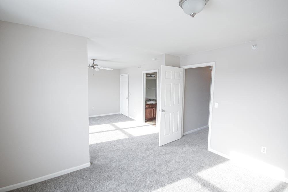 A white room with a carpeted floor and a doorway leading to another room.