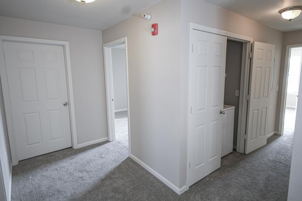 A room with white doors and a red fire alarm.