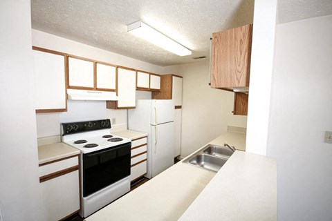 A kitchen with white appliances and wooden cabinets.
