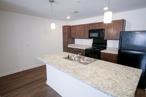 A kitchen with a granite countertop and a black refrigerator.
