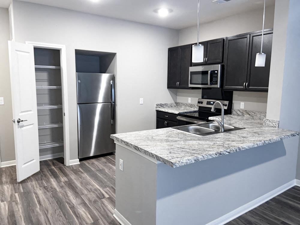 Kitchen with white walls, black cabinets and silver refrigerator at Promenade Luxury apartments in Beaumont, Texas