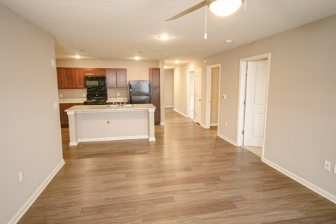 A spacious living room with a kitchen area in the background.