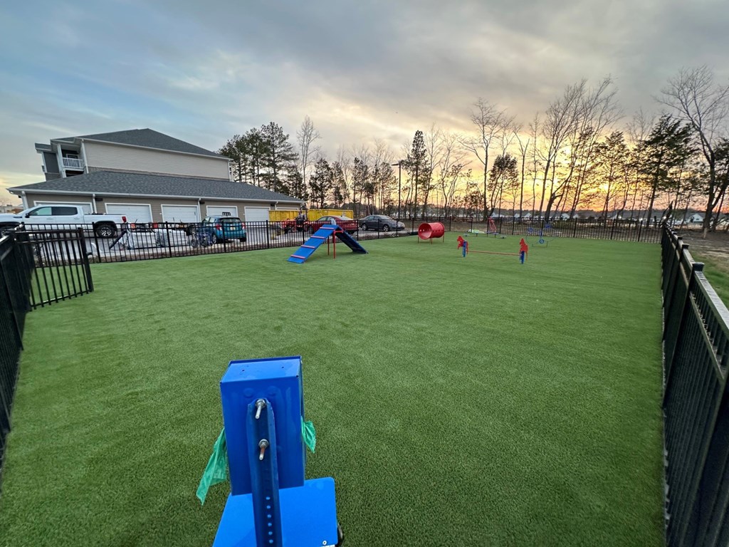 Dog park with a fence with obstacles at Aurora apartments