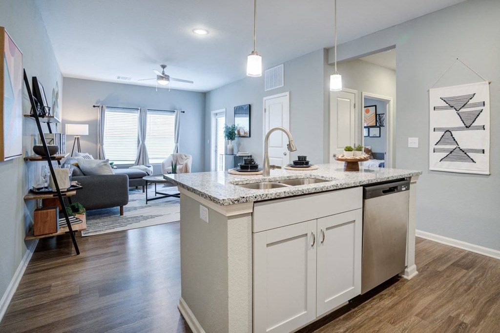 a kitchen with an island and a sink in front of a living room with a couch