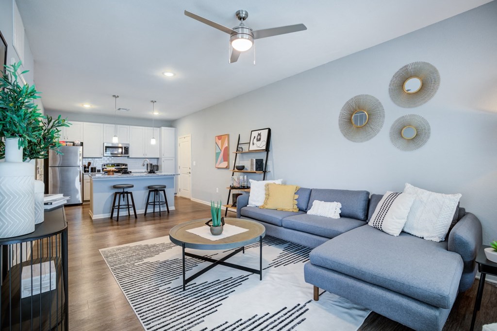 a living room with a couch coffee table and a kitchen in the background