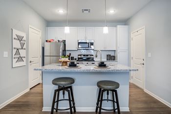 A kitchen with a bar stool in front of the island.