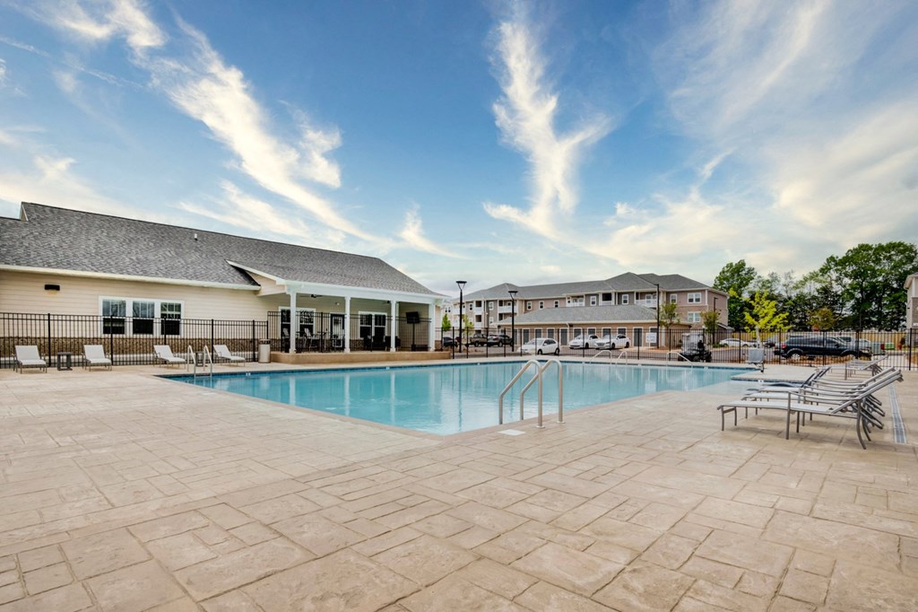Swimming pool with chaise lounge chairs and Aurora's clubhouse in the background