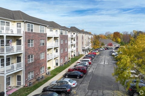 A row of apartment buildings with cars parked in front.
