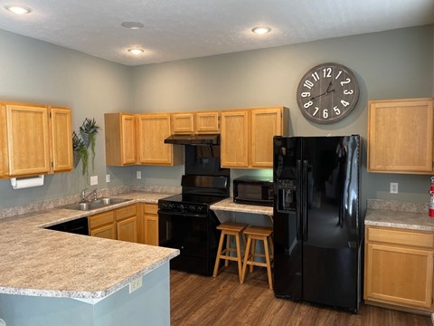 A kitchen with a black refrigerator and wooden cabinets.