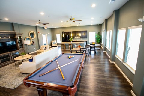 A pool table is in the middle of a room with a television and a couch.