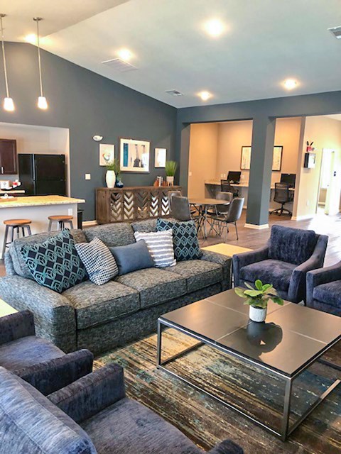 A living room with a grey couch and a glass coffee table.