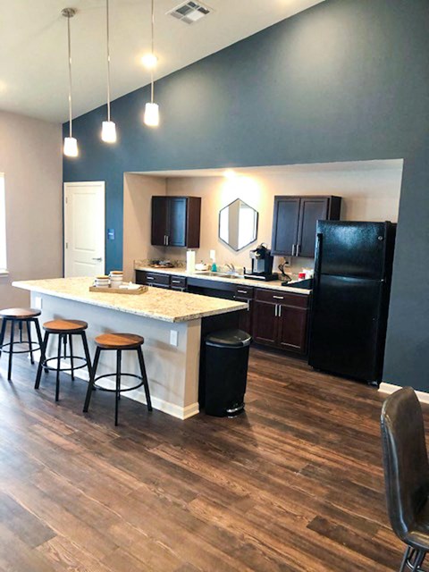 A kitchen with a black refrigerator and wooden floors.