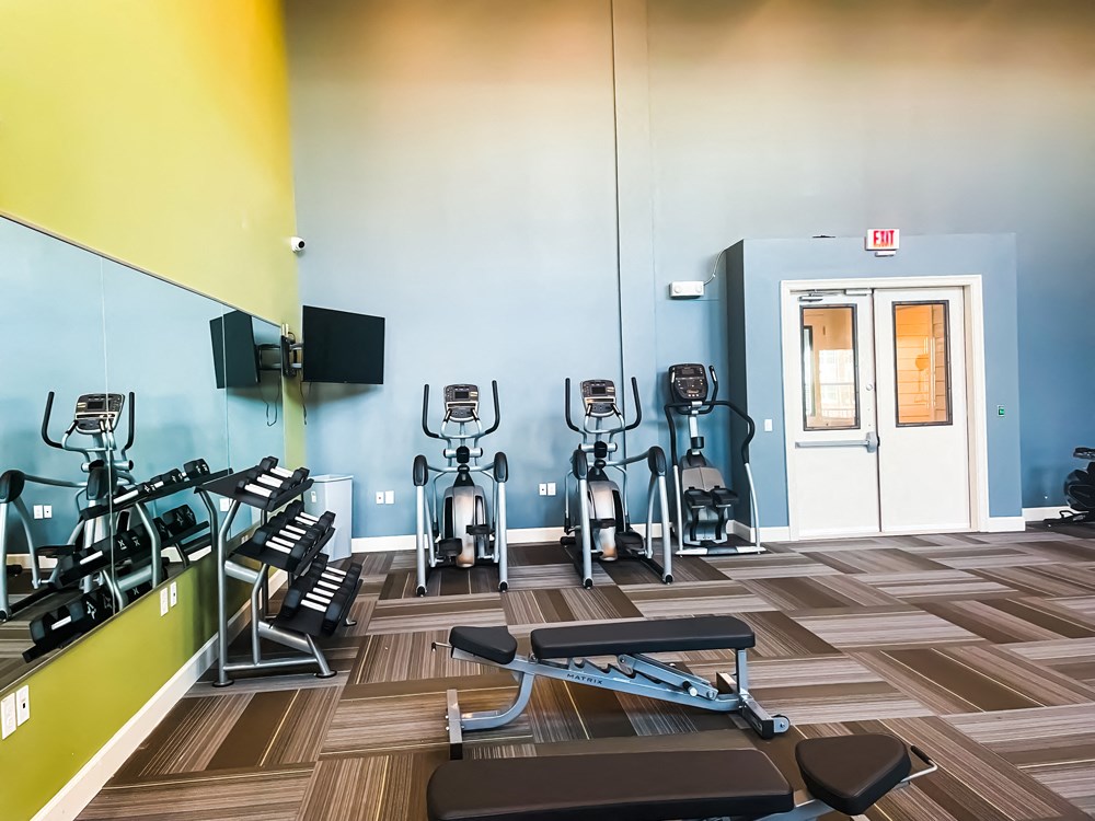 The fitness center with ellipticals, mirror, and TV at The Lofts at Canterbury in Slidell, Louisiana