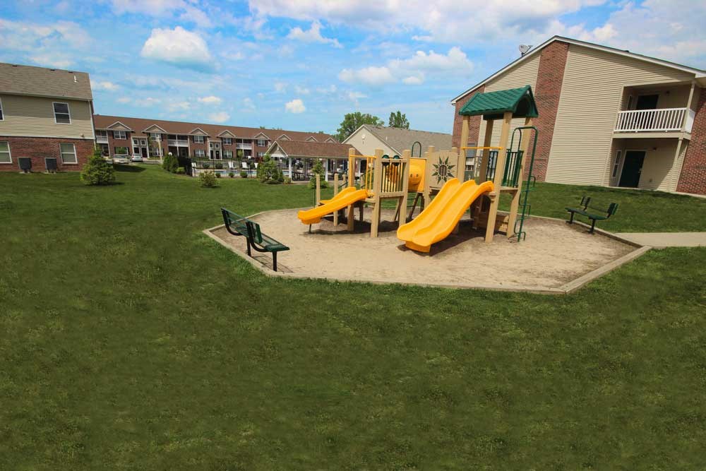A playground with a yellow slide and green roofed structure.
