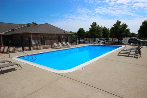 a swimming pool with chairs around it in front of a house