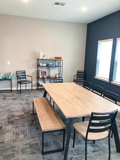 A room with a table, chairs, and a bookshelf.