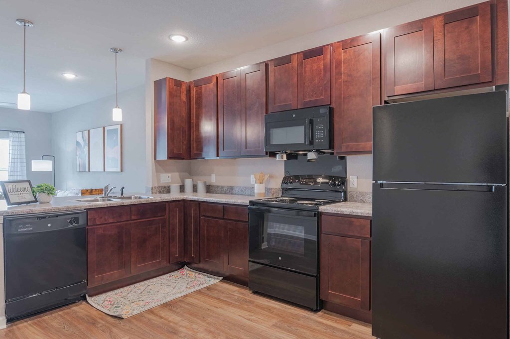 A kitchen with dark wood cabinets and black appliances