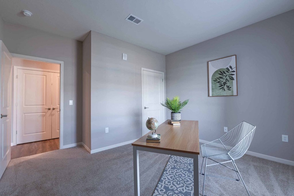 Adesk with a chair in a room with a door to a hallway at Crossing at Grove City apartments in Grove City, OH