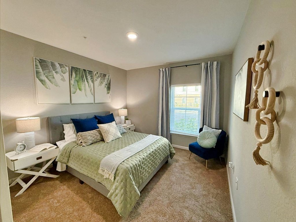 A bedroom with a large bed and a blue chair at flats at sundown luxury apartments in north port fl