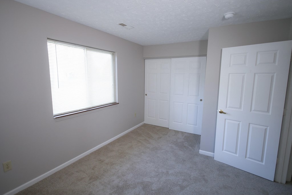 an empty bedroom with two doors and a window at Frankfort Place apartments in Frankfort, Indiana