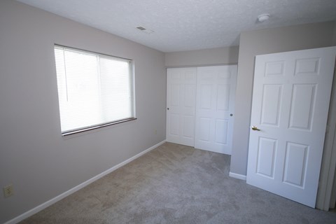 an empty bedroom with two doors and a window at Frankfort Place apartments in Frankfort, Indiana