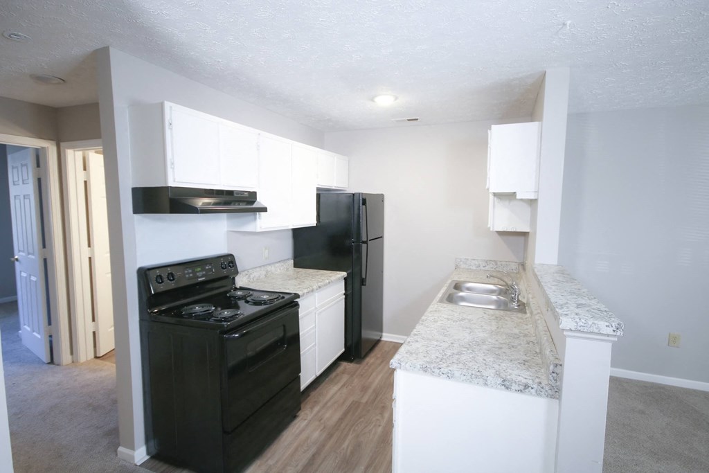 an empty kitchen with black appliances and white counter tops at Frankfort Place apartments in Frankfort, Indiana