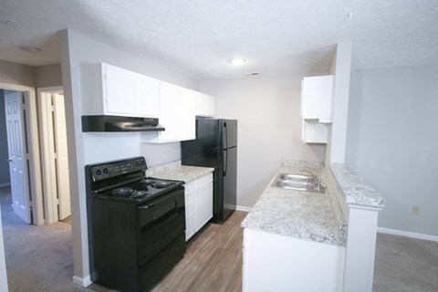 an empty kitchen with black appliances and white cabinets