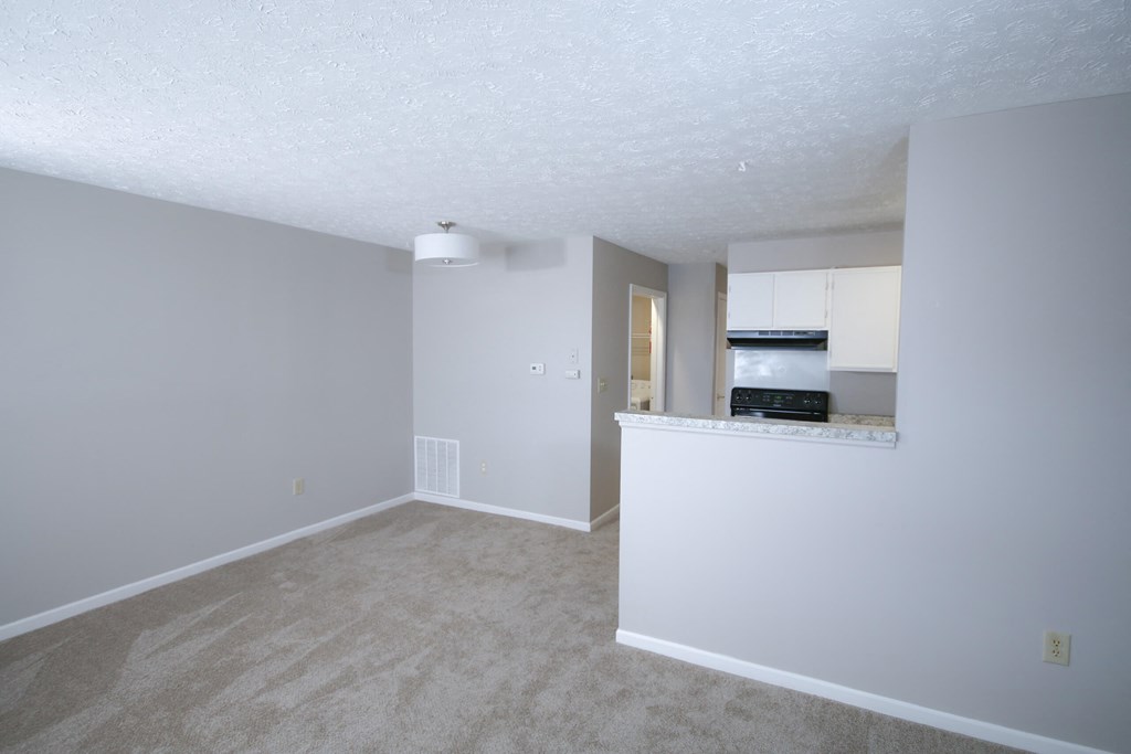 an empty living room and kitchen with white walls and carpet at Frankfort Place apartments in Frankfort, Indiana